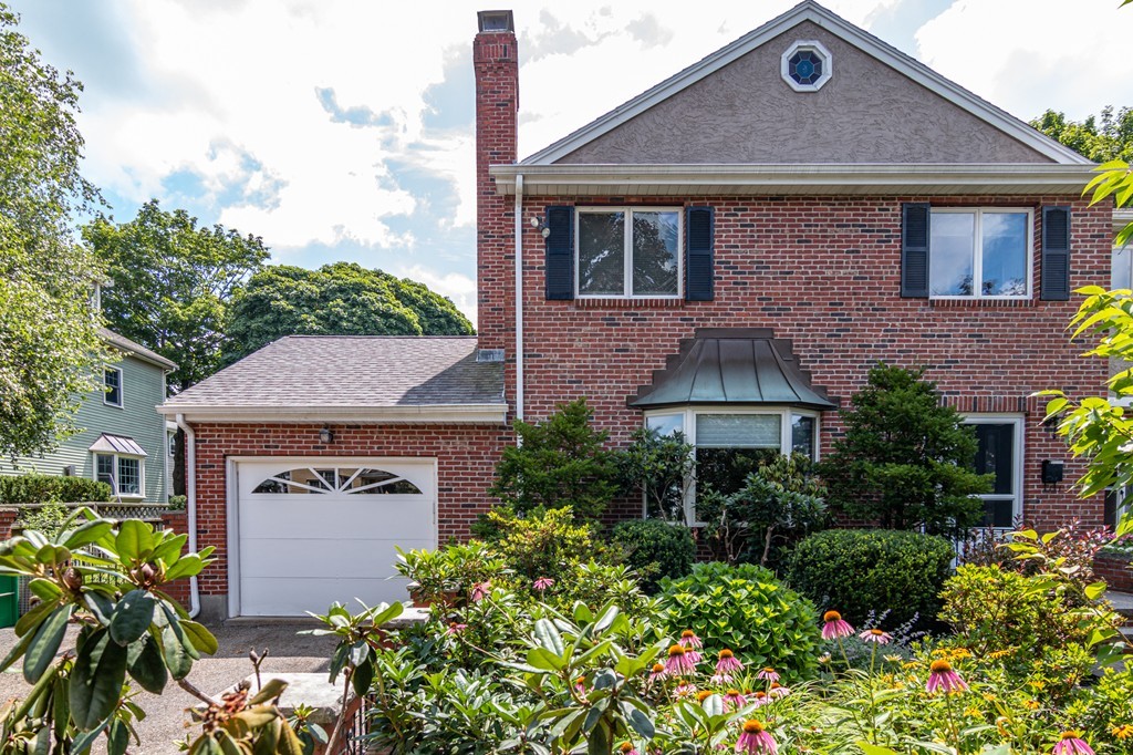 Exterior of brick townhouse at 12 Churchill Street, Newton, with garage and lush gardens